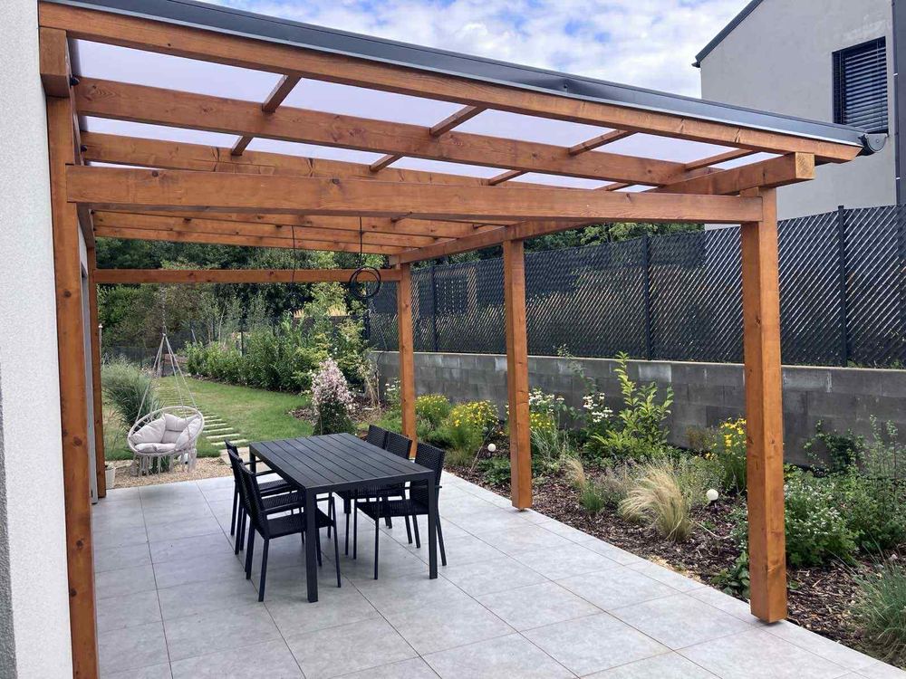 Pergola s polykarbonátovým zastřešením nad dlážděnou terasou
